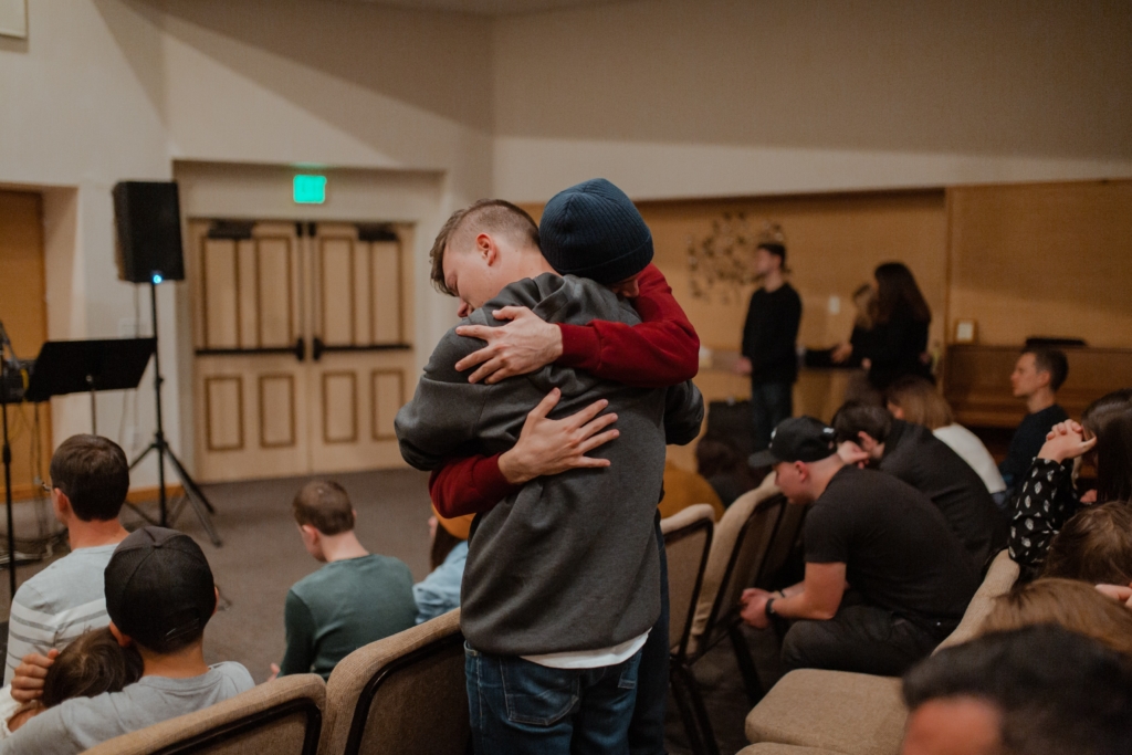 two men hugging in addiction counseling group